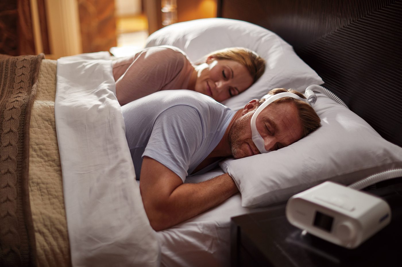 CPAPを装着して安らかに眠る男性と、隣で静かに眠るパートナー